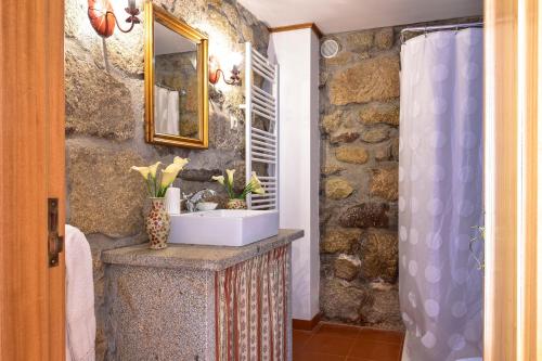 ein Badezimmer mit einem Waschbecken und einer Steinmauer in der Unterkunft Casa da Quinta do Cruzeiro in Fontoura