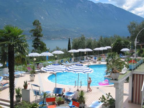 a pool with umbrellas and people in a resort at Hotel Riviera Panoramic Green Resort in Limone sul Garda