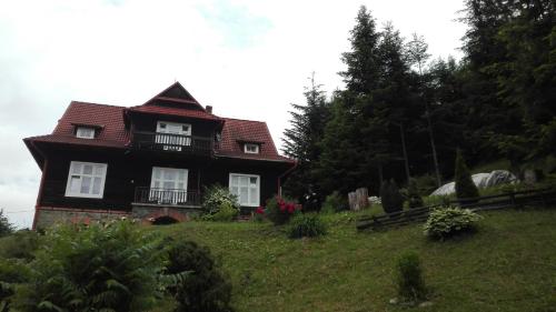 a black house with a red roof on a hill at Willa Marylka in Piwniczna