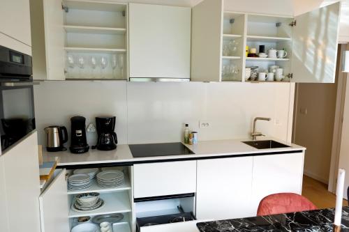a kitchen with white cabinets and a sink at Modern Appartment in the Heart of Ghent in Ghent