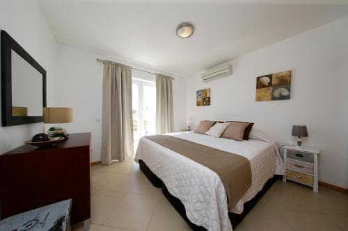 a bedroom with a bed and a large window at Apartamento Laranjas Garden in Cabanas de Tavira