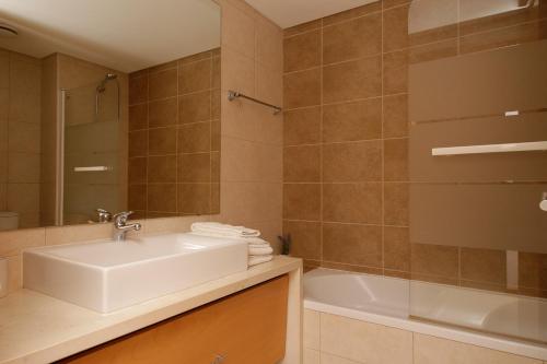 a bathroom with a sink and a bath tub at Apartamento Laranjas Garden in Cabanas de Tavira