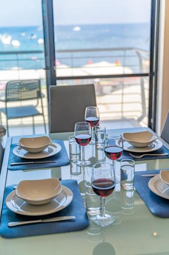 a table with glasses of wine and a table with a view at Marsalforn Apartment Del Mar in Marsalforn