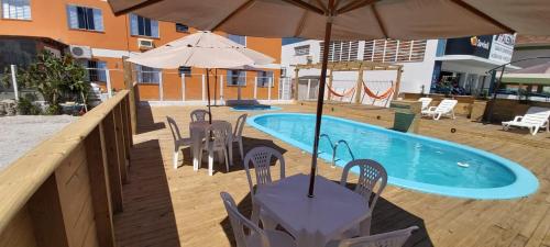 a table with an umbrella next to a swimming pool at Pousada Milani in Florianópolis