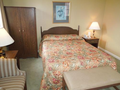 a hotel room with a bed and a chair at Bridges Guest Quarters in Abbottstown