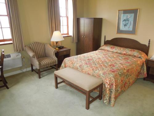 a hotel room with a bed and a chair at Bridges Guest Quarters in Abbottstown