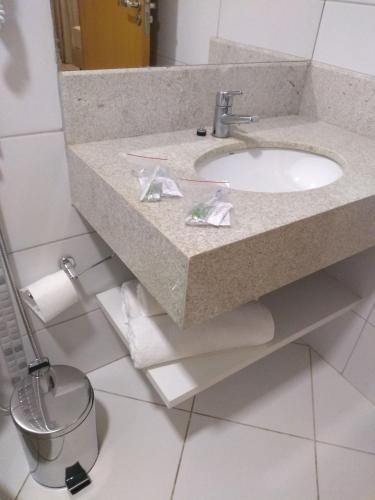 a bathroom with a sink and a trash can at Barretos Thermas Park - CondoHotel in Barretos