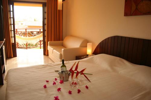 a bed with a bottle of wine and flowers on it at Hotel Aconchego Porto de Galinhas in Porto De Galinhas