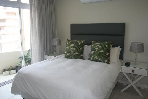 a bedroom with a large white bed and a window at 71 Sea Lodge Beachfront Apartment in Durban