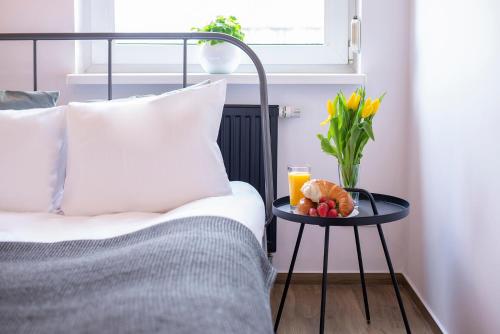 a bed with a table with a glass of orange juice and flowers at Apartament Alicante Górny Sopot by Renters in Sopot