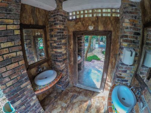 a stone bathroom with two sinks and two mirrors at Hotel Hacienda Gualanday in Villavicencio
