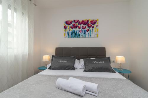 - une chambre avec un lit avec deux oreillers et un tableau dans l'établissement Apartment Ferias, à Trogir