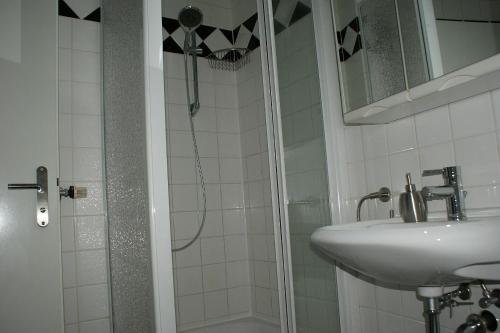 a bathroom with a shower, sink, and mirror at Hotel Garni Aaberna in Berlin
