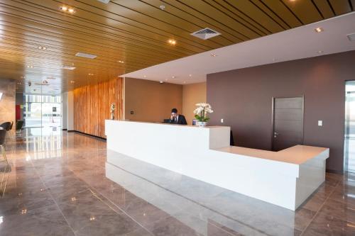 a man standing at a reception desk in a lobby at MDS Hotel Chillan in Chillán