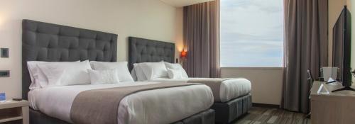 a hotel room with two beds and a large window at MDS Hotel Chillan in Chillán