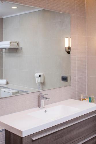 a bathroom with a sink and a large mirror at MDS Hotel Chillan in Chillán