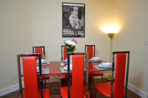 a dining room with a table and red chairs at Epicsa - 3 Bedroom Family & Corporate Stay, Garden and FREE parking in Cambridge