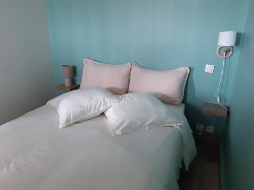 a bed with white pillows and a blue wall at COSYLOC studios in Cergy
