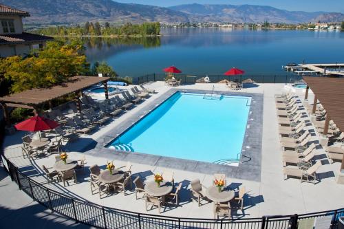 a patio area with a pool, chairs, and tables at Walnut Beach Resort in Osoyoos