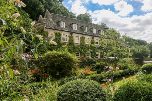 an old house with a garden in front of it at The Swan Hotel in Bibury