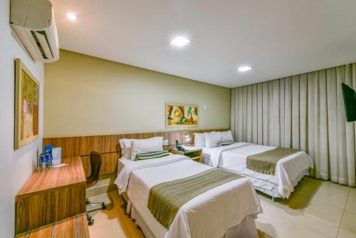 ゴイアニアにあるPlaza Inn Breeze Aeroportoのベッド2台と机があるホテルの部屋