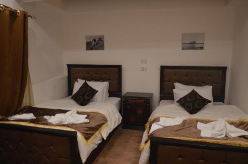 a bedroom with two beds and a night stand at Pyramids Top Inn in Cairo