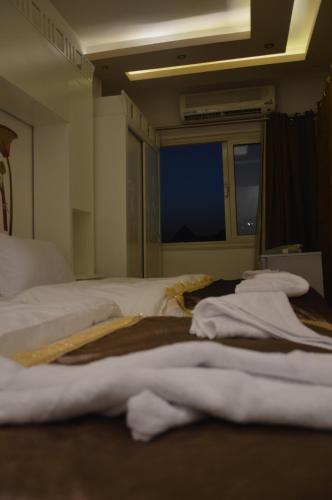 a bedroom with a bed with white sheets and a window at Pyramids Top Inn in Cairo
