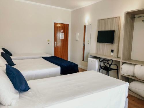 a hotel room with two beds and a tv at Sense Flat Hotel in Araucária