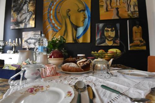 a table with plates of food and paintings on the wall at A Casa dell'Artista ViKi in Iesi