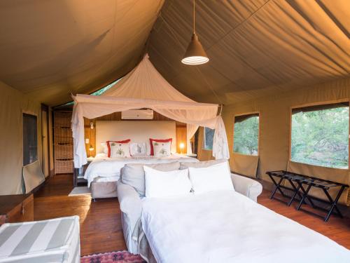 a tent bedroom with two beds and a couch at aha Thakadu River Camp in Madikwe Game Reserve