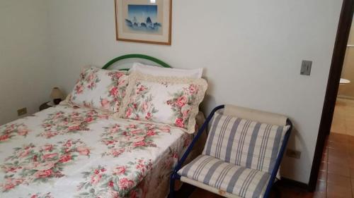 a small bedroom with a bed and a chair at Ubatuba Tenório apto térreo 6 pess in Ubatuba