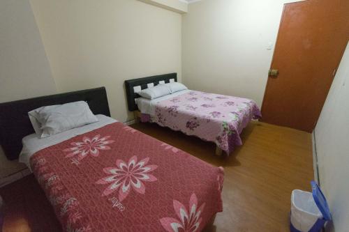 Habitación pequeña con 2 camas y puerta en Hospedaje el viajero-Aeropuerto, en Lima