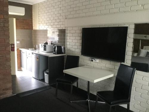 a kitchen with a table and chairs and a television at Albury Townhouse Motel in Albury