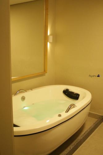 a white bath tub in a bathroom with a mirror at Café Palace Hotel in Três Pontas