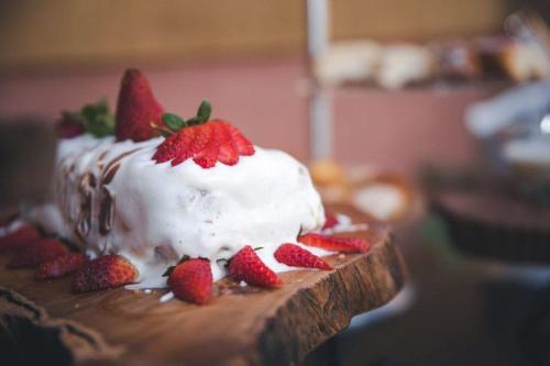 a cake with strawberries on top of it on a table at Café Palace Hotel in Três Pontas
