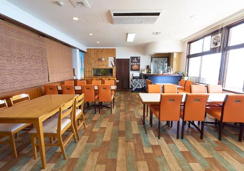 a dining room with tables and orange chairs at Minshuku Atsuhama in Sumoto