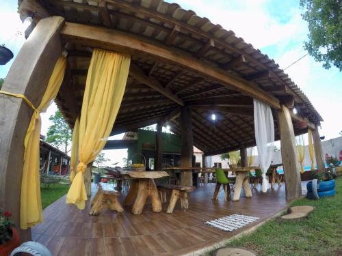 a pavilion with tables and curtains on a wooden deck at Pousada Cantinho de Casa in Nobres