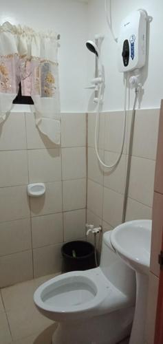 a bathroom with a white toilet and a shower at Lei Kendee in Digos