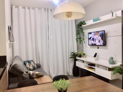 Apto 3 quartos em Araranguá في أرارانجوا: غرفة معيشة مع أريكة وطاولة مع تلفزيون