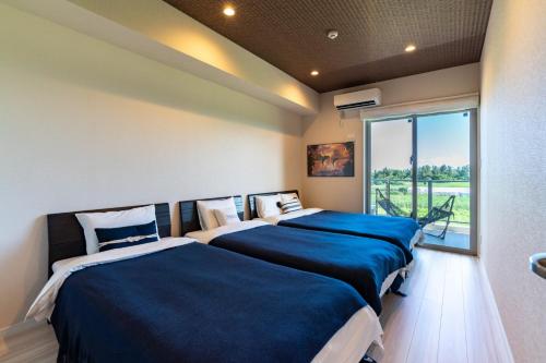 two beds in a room with a large window at Ocean Resort Maeda / Vacation STAY 3223 in Onna