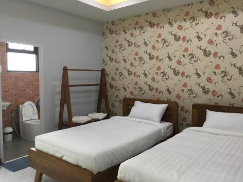 a bedroom with two beds and a wall with flowers at Money Grand Home in Ban Don Muang