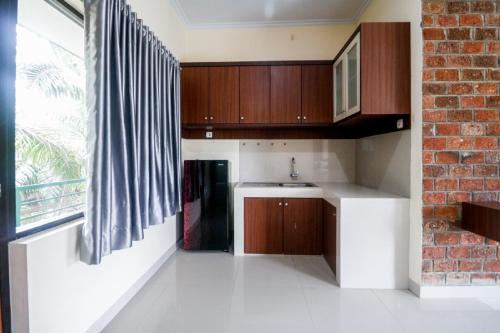 a kitchen with wooden cabinets and a brick wall at RedDoorz Plus near Kualanamu Airport Medan in Medan