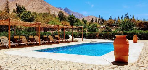 a swimming pool with chairs and a gazebo at Refugios Pisco Elqui in Pisco Elqui