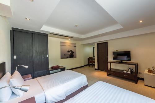 a bedroom with two beds and a flat screen tv at Hotel Tropicana Pattaya - SHA Extra Plus by D N A in Pattaya