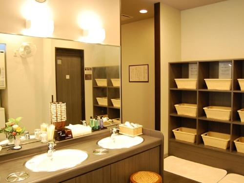 a bathroom with two sinks and a large mirror at Hotel Route-inn Natori in Natori