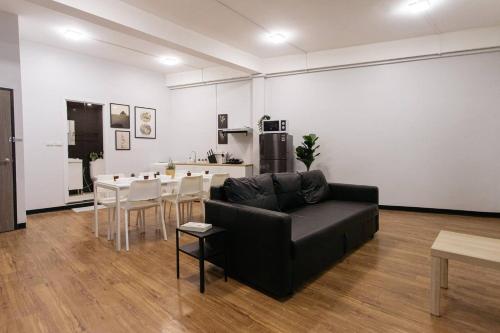 a living room with a black couch and a table at U3 Large 2 Bedroom Full kitchen near BTS Udomsuk in Bangkok