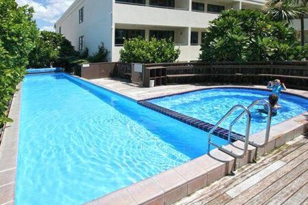 a large blue swimming pool in front of a building at Oceanside Apartment in Mount Maunganui
