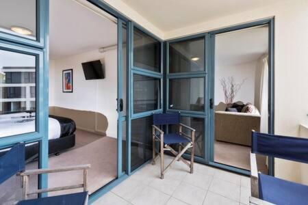 a room with a bed and a room with glass doors at Oceanside Apartment in Mount Maunganui