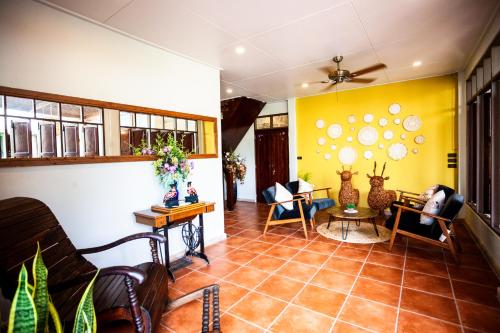 a living room filled with furniture and a yellow wall at Baan Suan Krung Kao in Phra Nakhon Si Ayutthaya