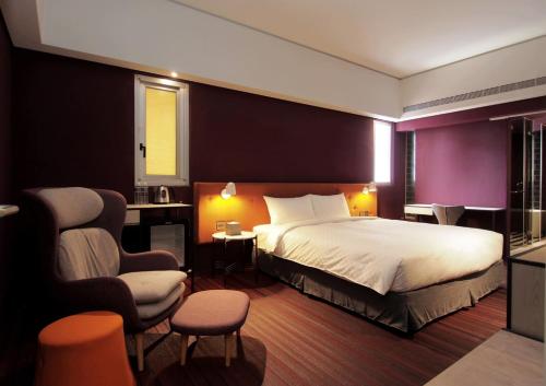 a hotel room with a bed and a chair at Ramble Hotel in Taichung